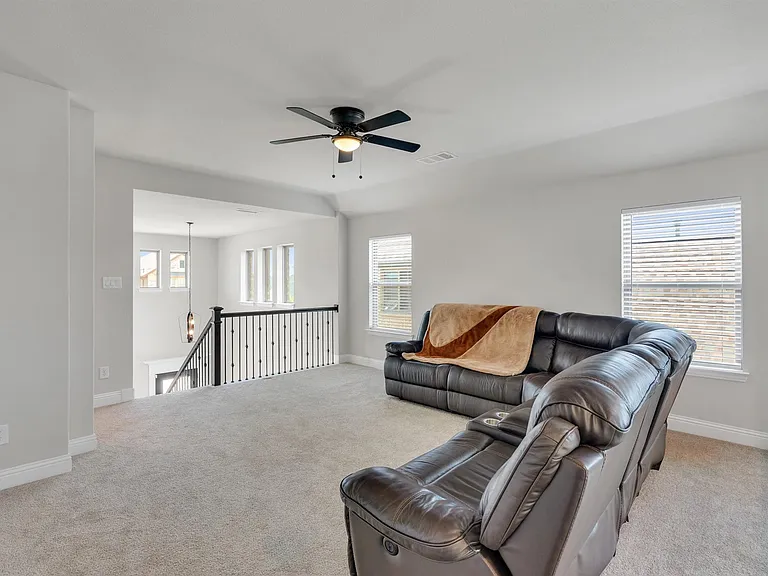 Spacious upstairs loft area featuring light gray carpeting and white baseboards