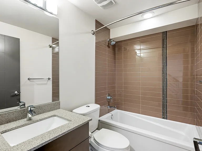 Full sized bathroom on entry level with tile surround bathtub and shower.