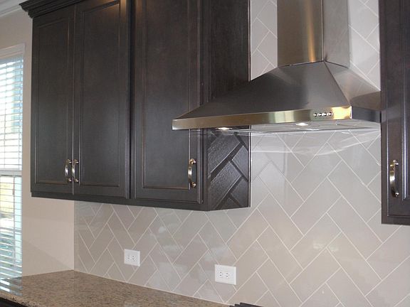 Designer Hood vented out with 42" cabinets , herringbone backsplash to ceiling