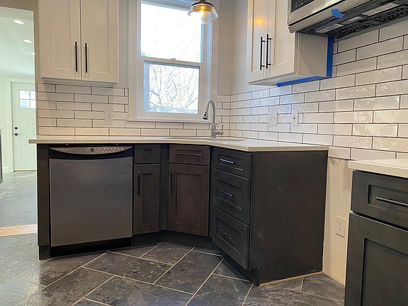 Dual-tone cabinets, designer herringbone floor tiles, quartz counter tops, under mount sink and designer back splash make this brand new kitchen gorgeous and functional. All appliances are stainless steel. Oven/range not yet installed in this photo. Floor