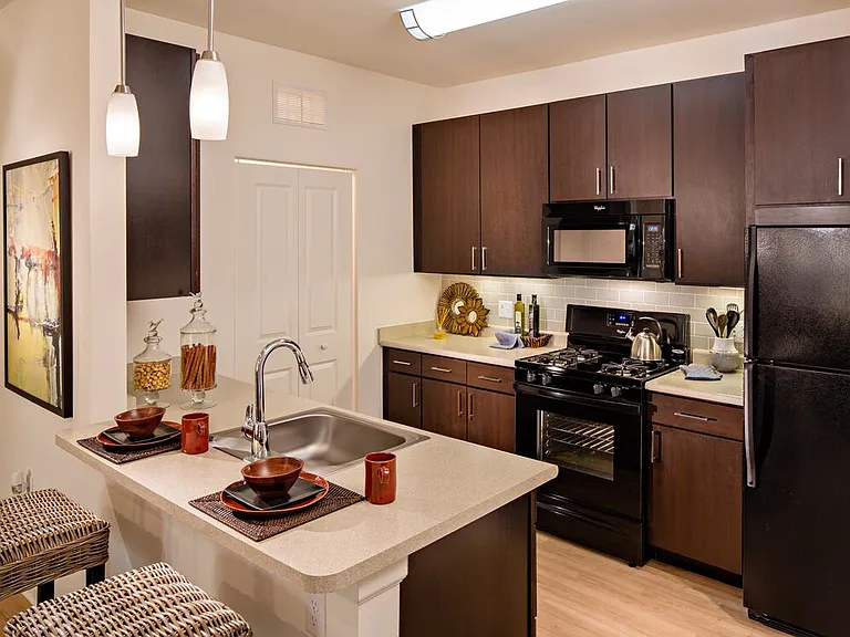 Kitchen with black appliances, espresso cabinetry, laminate countertops, and hard surface flooring