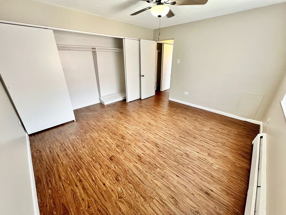 Spacious bedroom with elegant wood flooring, ample closet space, and a ceiling fan offering comfort and style.