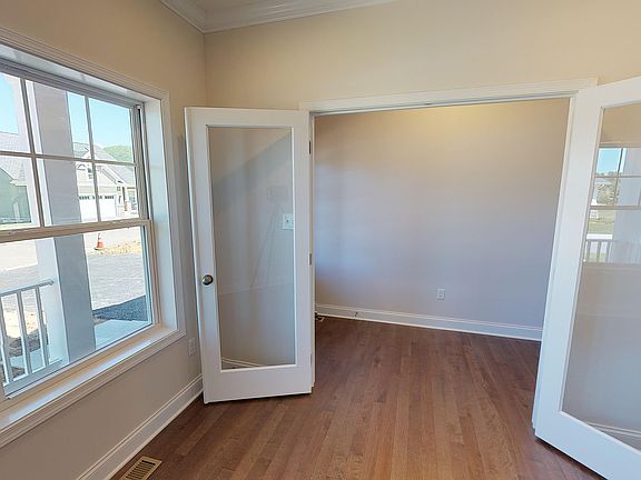 Double french door entry into a main level study with hardwood floor and large windows