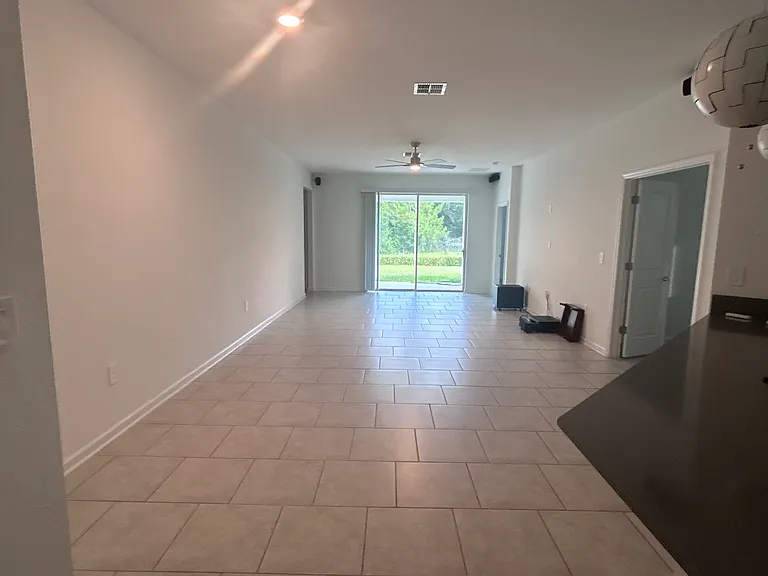 View to dining and living room with door to covered patio and peaceful backyard