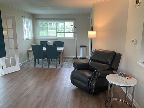 Living room facing backyard. Recliner, marble end table, dining room table.