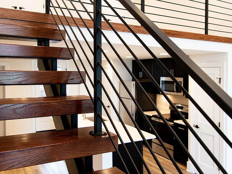 Experience the elegance of this contemporary space with a beautiful wooden staircase and a chic open kitchen.