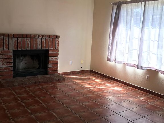 The living room, adorned with a cozy fireplace and a window offering a view of the front lawn, showcases tile flooring for effortless upkeep.