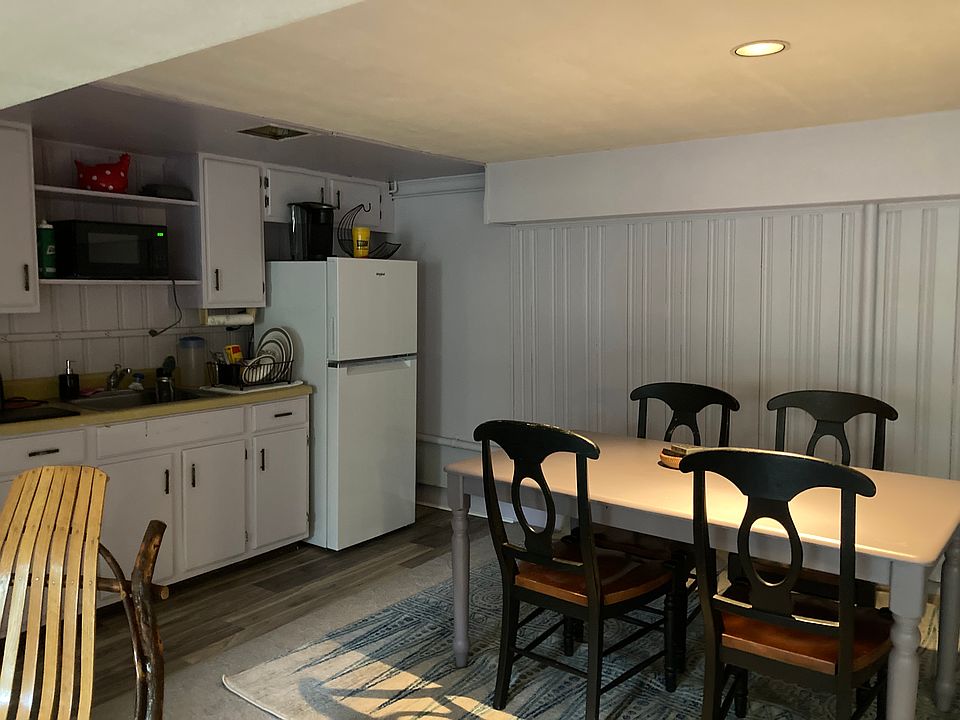 Kitchenette with oven, fridge, shelving and dishes.