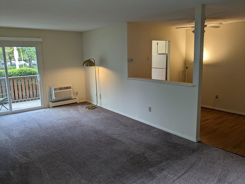 The living room, facing the dining room/kitchen. Entryway is behind and to the right, patio through sliding doors to the right.