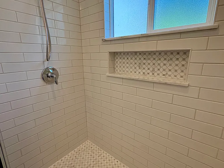Spacious shower with mosaic marble floor and niche