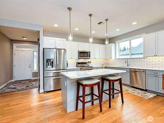 As you enter the kitchen area, you're greeted by the elegance of quartz countertops that catch the light beautifully. The cabinets, painted in a soft, inviting hue, create an airy and bright atmosphere, while offering plenty of storage for all your culinary essentials. The layout includes inviting bar seating, perfect for casual hangouts and lively conversations, making this space both functional and welcoming for family and friends.>