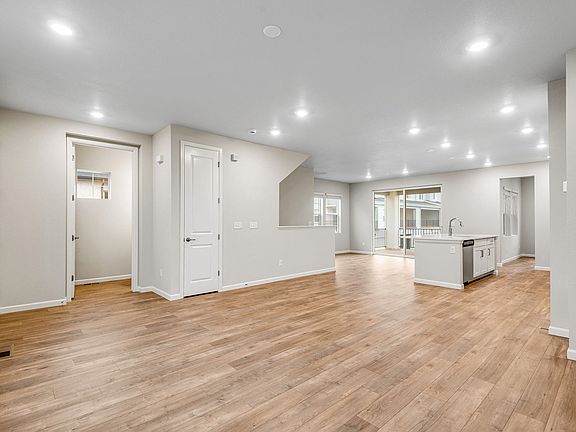 Great room looking towards kitchen and dining with wide-plank laminate wood color floor
