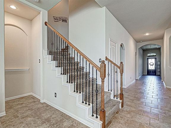 A view from the family room looking towards the front of home. Notice the brick patterned tile flooring and pretty staircase that leads to the game room.