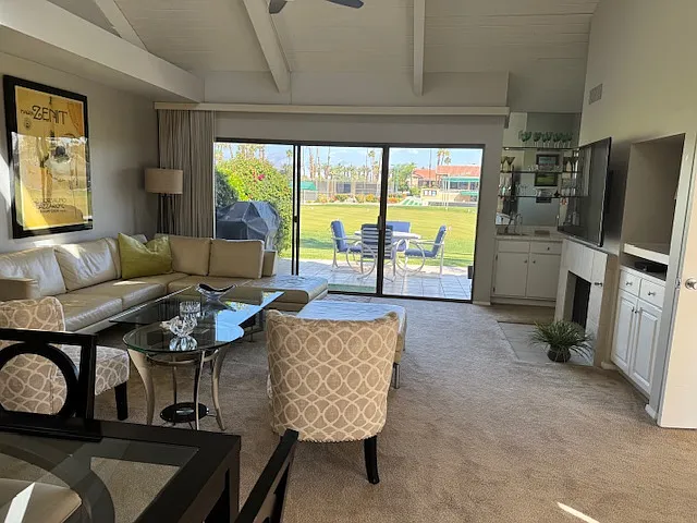 Living room with vaulted ceiling looking out to back view.