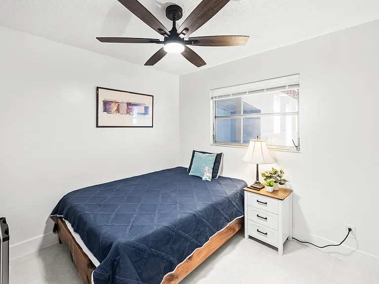 Private bedroom with a comfortable bed, ceiling fan, and bedside storage, plus a window for natural light.