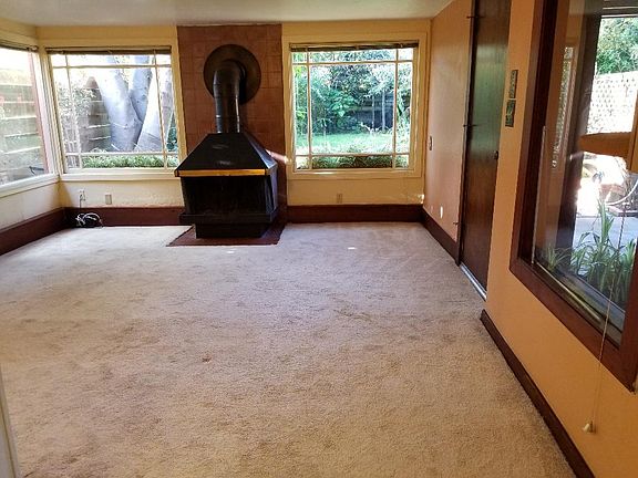 Large living room with lots of windows out to the garden and front door.