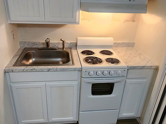 Kitchen with new cabinets, sink, faucet, and flooring.
