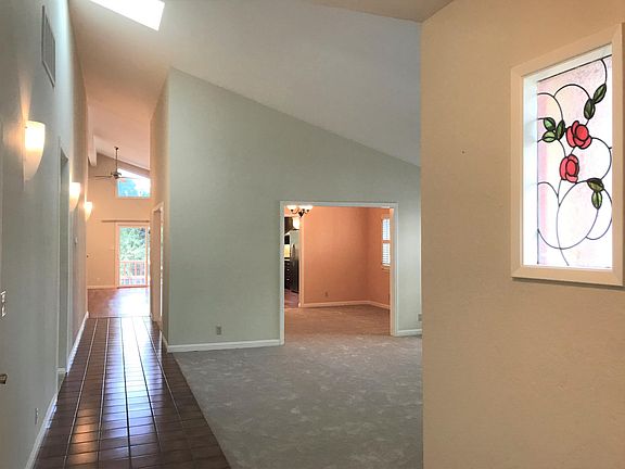 Entry foyer with a rose themed stained glass. High cathedral-like ceiling throughout the length of the house.