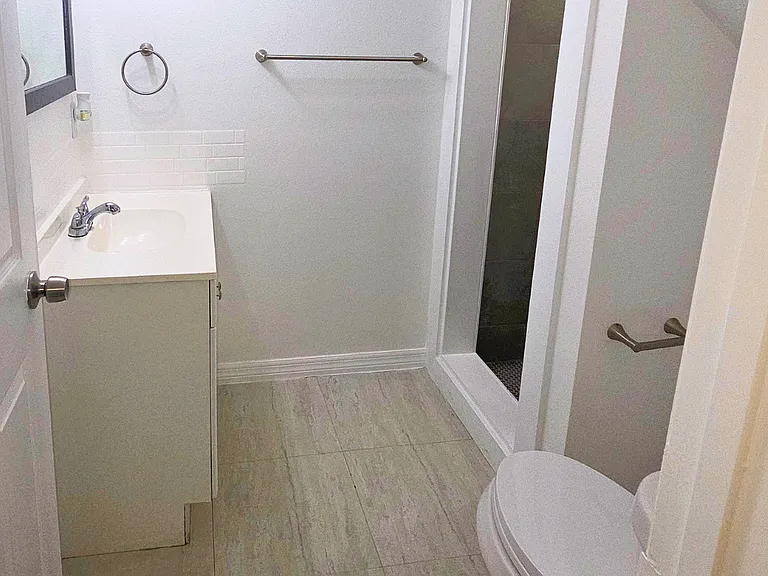 Spotless bathroom with a vanity, mirror, sink, toilet, and towel racks.