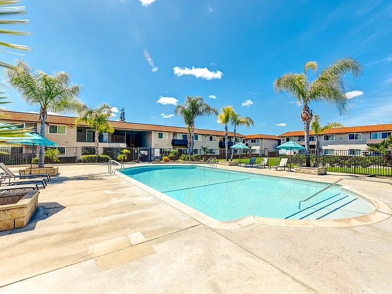a swimming pool with palm trees and a building in the background
