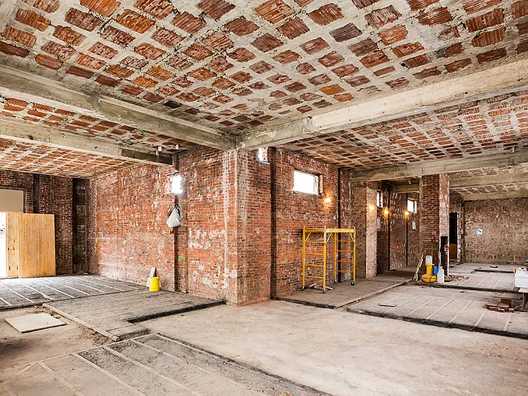 Before: L-shaped room with exposed brick during renovation