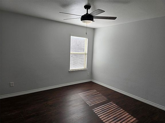 Empty room featuring ceiling fan and dark hardwood / wood-style floors