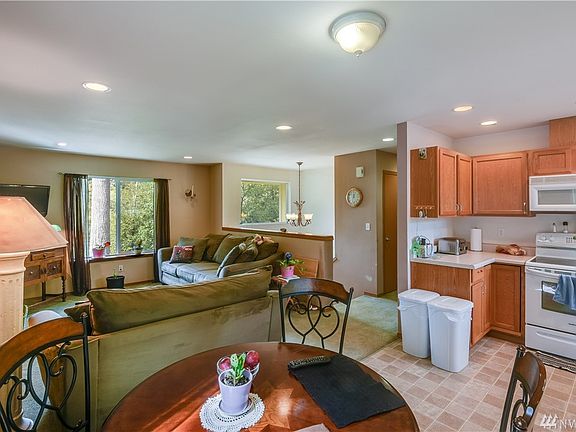 A bright and light well functioning kitchen is highlighted by recessed lighting and white appliances. 