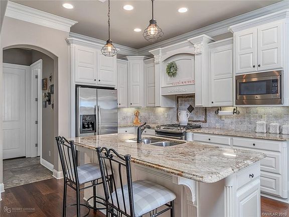 Stainless appliances, neutral colors, wood floors, island seating, and granite countertops.