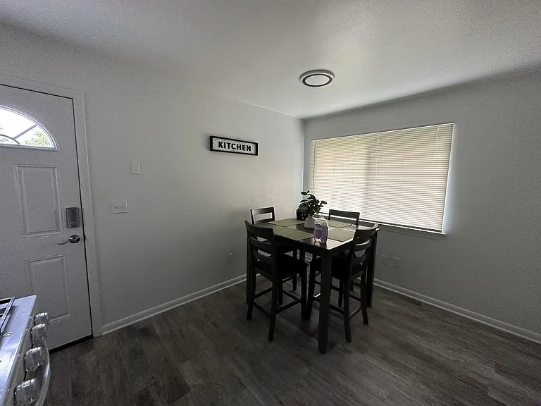 Dedicated dining nook with a four-seat table, durable flooring, and a large window with blinds for everyday meals.