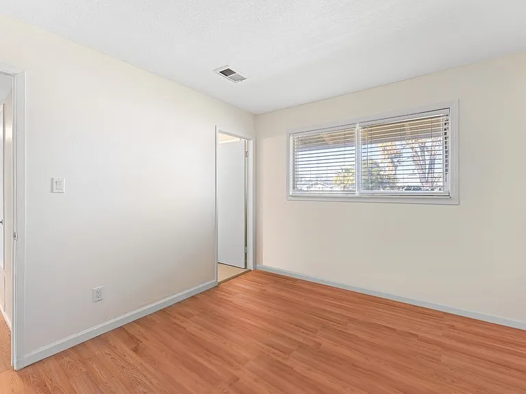 Master bedroom freshly painted, featuring hardwood floors, a large window, spacious closet, and en-suite bathroom.