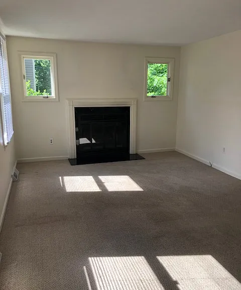Sun filled family room with 4 large windows and a beautiful black marble fireplace that is perfect for relaxing or entertaining.