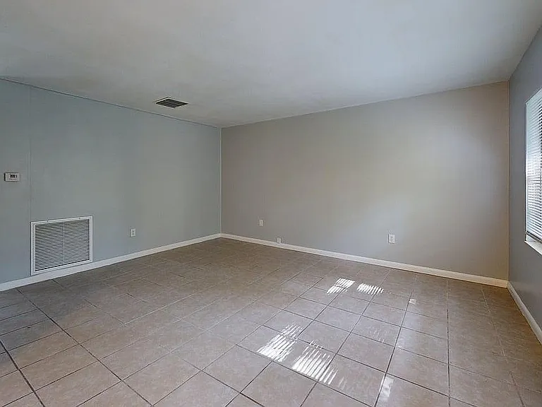 Bright, open living space with large windows and neutral tile flooring, perfect for customization and natural light enjoyment.