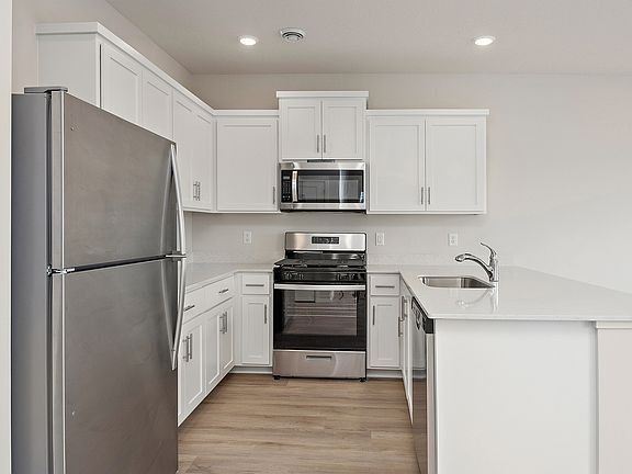 The kitchen has stainless steel appliances and plank flooring,