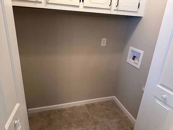 Laundry closet with washer and dryer hookups and cabinets above.