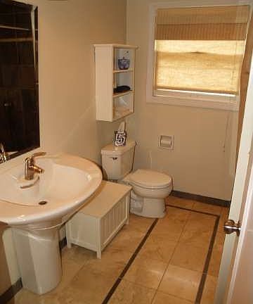 Oversize pedestal sink with travertine flooring and slate shower.