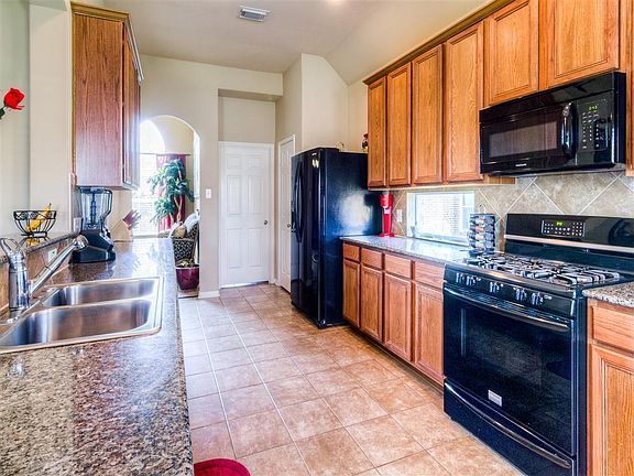 A cooks kitchen delivering 42in cabinets, granite counters, oversized tile flooring and a lovely her