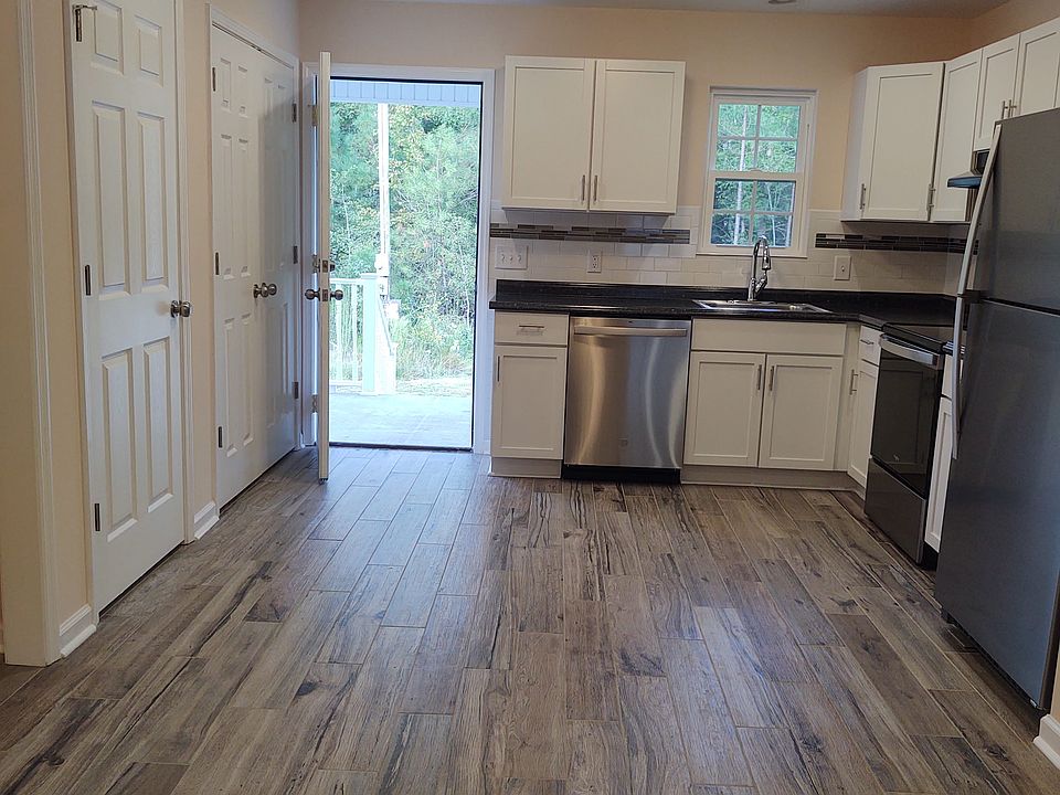 Open concept living room, dining area & kitchen tile flooring throughout the apartment. View to back porch.