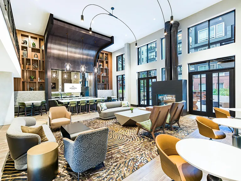 Grand community lounge with floor-to-ceiling windows, sculptural fixtures, and a mix of seating areas arranged for hosting, relaxing, and shared moments.