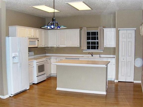 Beautiful kitchen with raised white cabinets, easy care wood look flooring. 