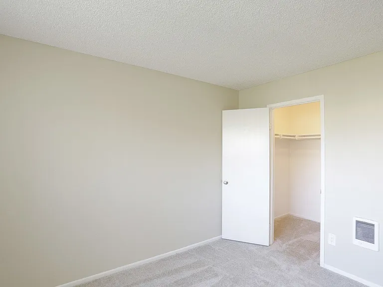 Carpeted bedroom with walk-in closet at Villa Pacific Apartments in Oceanside, California.