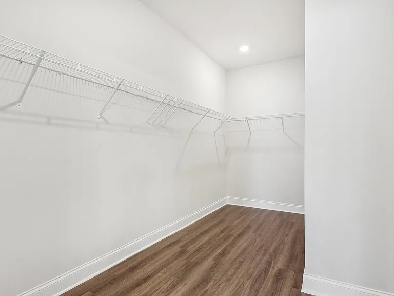 Primary suite with a full walk in closet featuring custom racks.