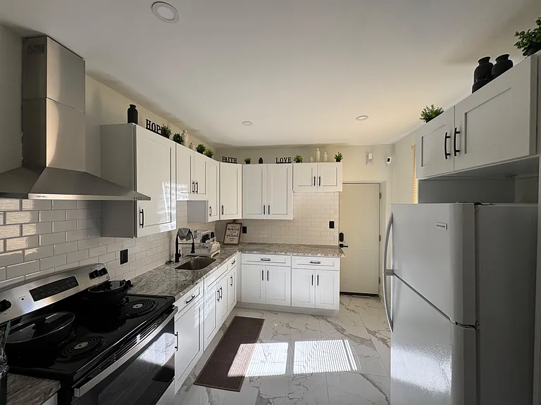 Galley kitchen with ample white cabinetry, subway-tile backsplash, and full-size appliances plus generous counter space.