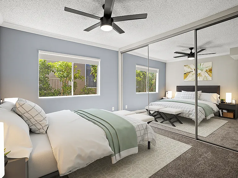 Carpeted bedroom with ceiling fan and large mirrored closets.