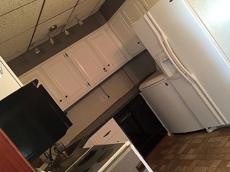 Photo of the kitchen before the laundry unit was installed. The refrigerator is now moved and built-in laundry is placed instead (see other images).