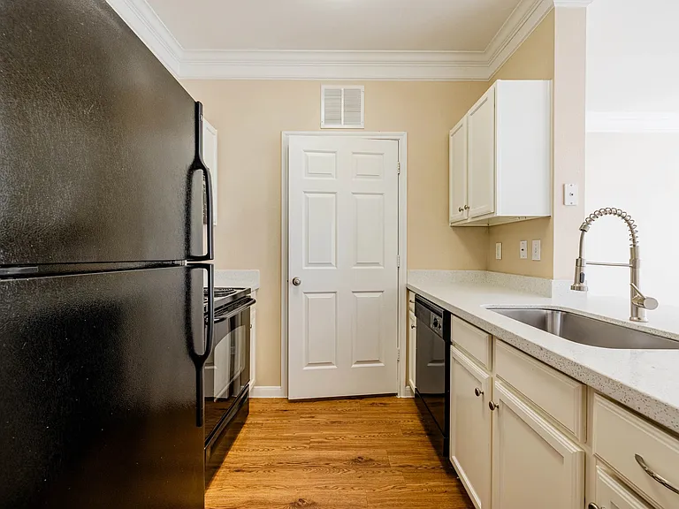 Chic kitchen with modern black appliances, sleek countertops, and elegant wood-style flooring. Chic kitchen with modern black appliances, sleek countertops, and elegant wood-style flooring.
