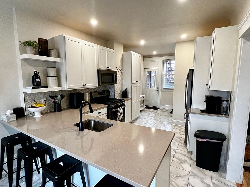 Professionally designed kitchen with hardwood cabinets, custom tile backsplash, new slate appliances, island with room for four bar stools and luxury engineered tile flooring
