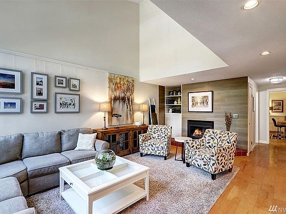 The spacious great room features vaulted ceilings, gas fireplace with shiplap wood surround, built-in white cabinetry and treed 