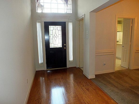 The foyer with leaded glass, a transom window and wood flooring.