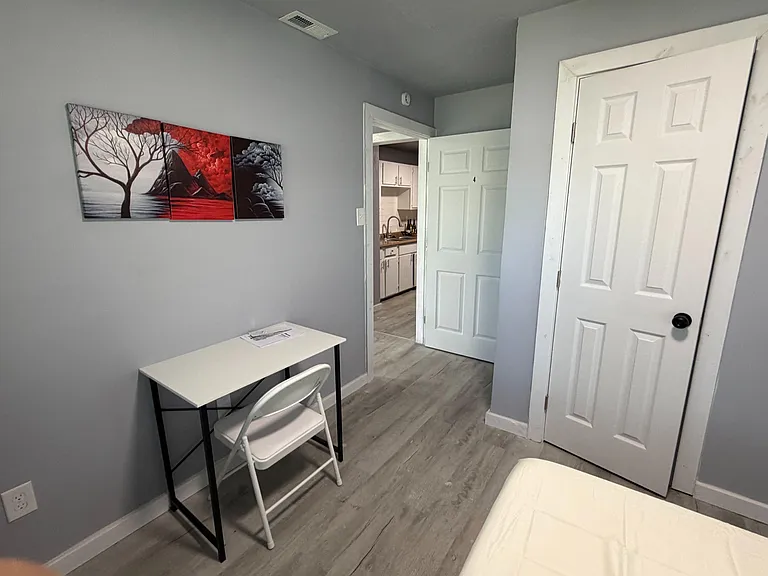 Private bedroom with easy-care flooring, a small desk area, and convenient access to the kitchen and nearby storage.