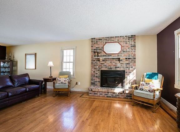 This home features TWO fireplaces.  This fireplace is wood burning and  has a brick surround and mantel.  There are gorgeous hardwood floors throughout the main level.  Notice the attention to detail in the inlay design on the floors.